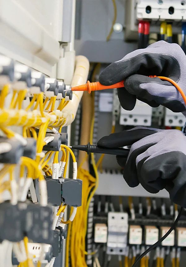Gloved hands working on yellow wiring in a control panel